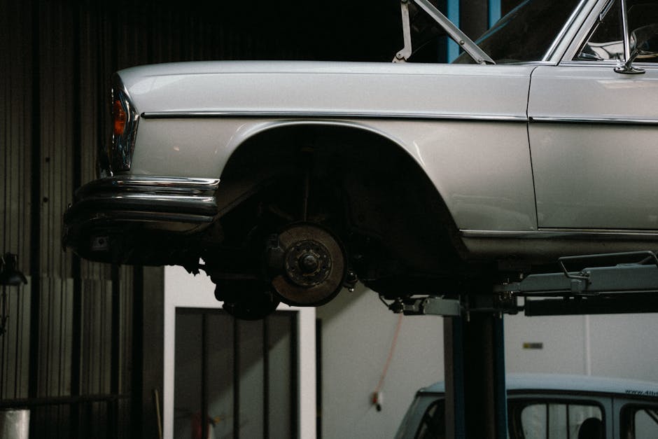 Механик осматривает подвеску автомобиля на подъёмнике в сервисном центре